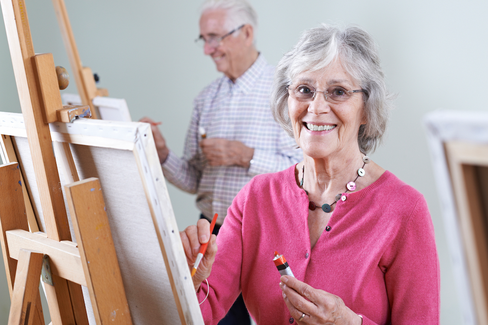 A smiling senior woman attends an art class