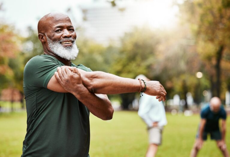 A smiling senior man stretches before a run in a park