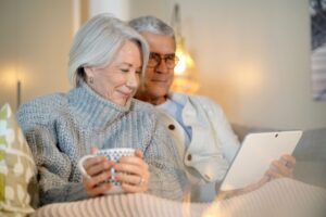 A senior couple wearing sweaters relaxing and looking at tablet